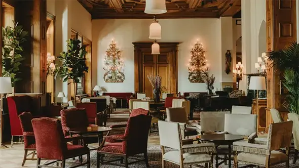 The historical interior of Le Grand Hall lobby at Badrutt’s Palace with crystal chandeliers and classic furniture.