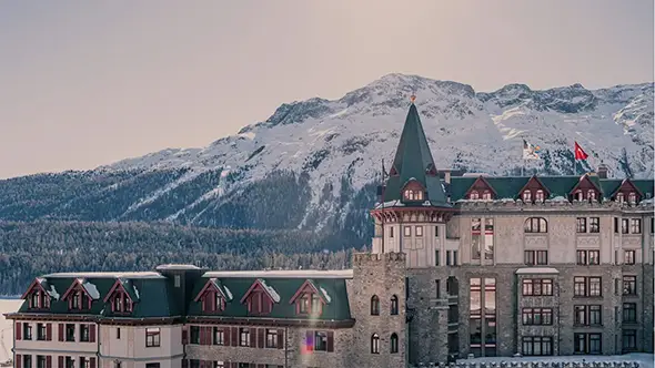 View of the famous tower and building of the Badrutt’s Palace hotel against the Engadin panorama.