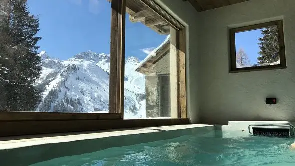 The luxurious indoor pool at Chalet Cesa del Louf with a view of the mountains.