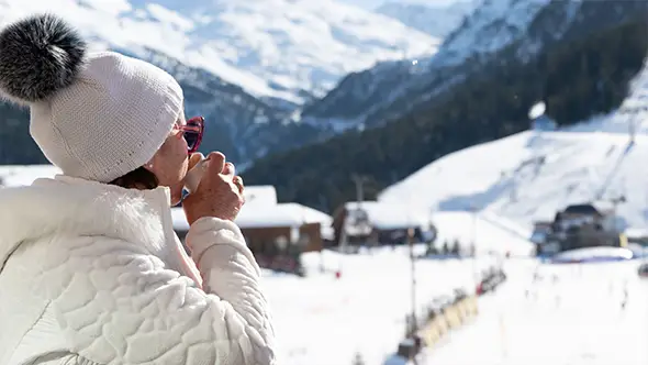 A guest enjoying a break on the terrace of Hotel de La Loze with a panoramic view of the snow-capped Alps.