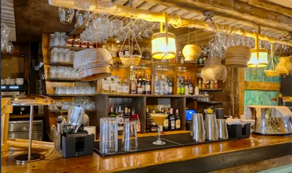 Pom Thai Bar Interior Warm minimalist bar interior of Pom Thai restaurant in Courchevel with woven lamps and wooden finishes.