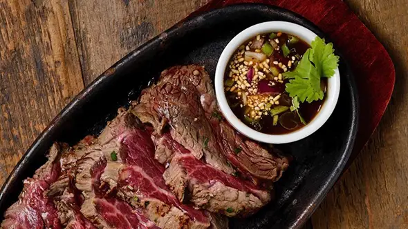 Thai-style grilled beef Juicy sliced grilled beef served with a savory Thai dipping sauce.