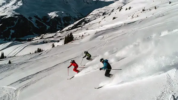 Three skiers descending fresh powder on a wide slope in Méribel on a sunny January day.