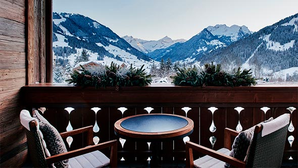 Cozy balcony with panoramic view of snowy Bernese Alps at The Alpina Gstaad
