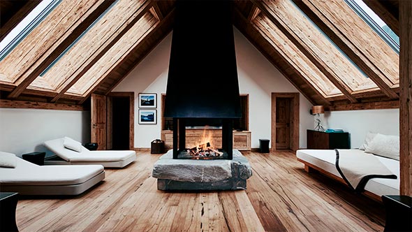 Relaxation area in Six Senses Spa at The Alpina Gstaad with central fireplace on stone pedestal