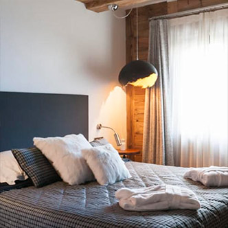 Cozy bedroom in Le Flocon apartment, Val d&rsquo;Is&egrave;re: fur pillows, bathrobes and warm lighting.