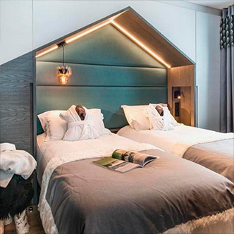 Modern bedroom in Chalet Izia apartment, Val d&rsquo;Is&egrave;re: twin beds with teal house-shaped headboard.