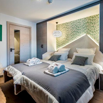 Modern bedroom in Chalet Skadi apartment, Val d&rsquo;Is&egrave;re: twin beds with green accent wall.
