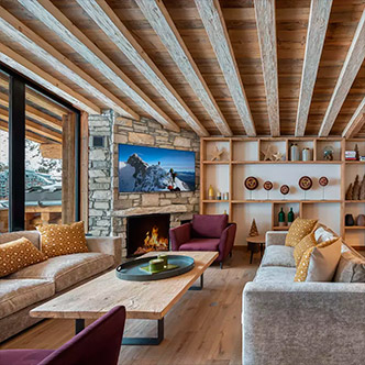 Cozy living room in Fl&egrave;che penthouse, Val d&rsquo;Is&egrave;re: stone fireplace, beige sofas and mountain view.