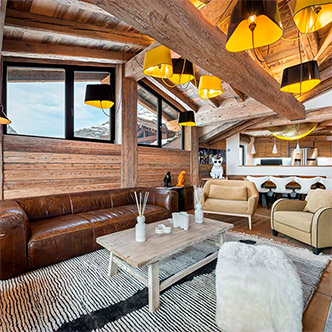 Luxury living room in Savoie penthouse, Val d&rsquo;Is&egrave;re: leather sofa, yellow lamps, high ceilings.