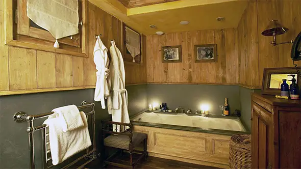Classic bathroom interior in a Meribel chalet featuring wood finishes, bathrobes, and soft evening lighting