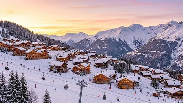 Panoramic view of the snowy village and ski lifts in Meribel during sunset