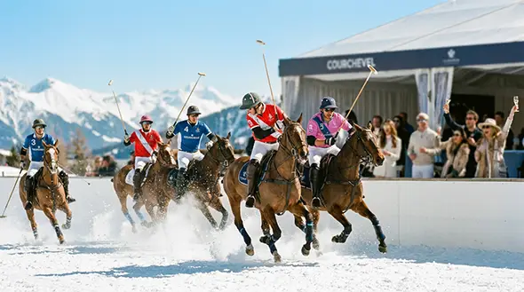 Players on horseback during a snow polo tournament.