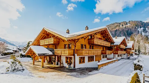 Exterior of luxury Ultima Collection chalets surrounded by the snow-covered Alps.