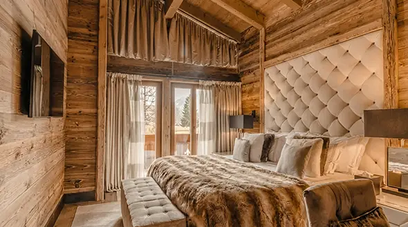 Luxury bedroom in Ultima Courchevel chalet with wooden finishes and panoramic windows.