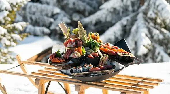 Sushi set from Zuma restaurant for in-chalet dining at Ultima Courchevel against snowy mountains.