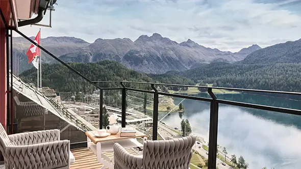 Balcony view of an alpine lake, mountains and a Swiss flag.