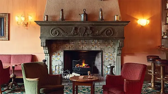 Cozy lounge area with a large stone fireplace and red armchairs.