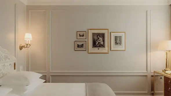 Bright hotel bedroom with classic interior and framed art.
