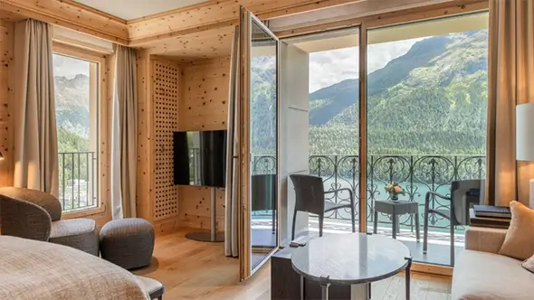 Hotel room with a cozy balcony and view of the lake and mountains.