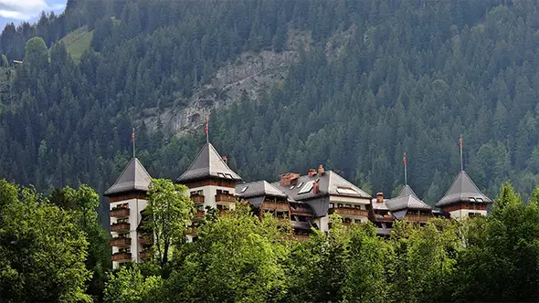 Large hotel in the Alps against a coniferous forest.