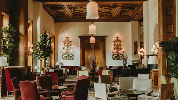 Luxury hotel lounge with red armchairs and a wooden ceiling.
