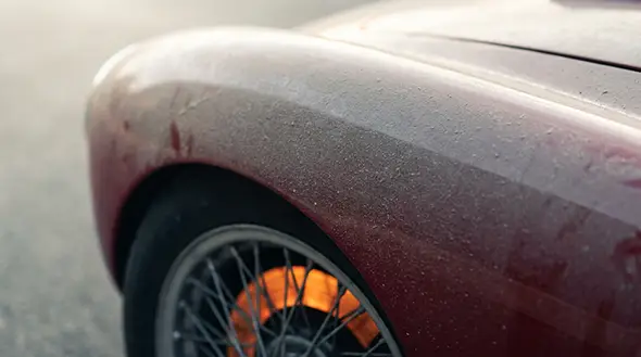 Noble road dust and glowing brakes of a classic sports car.