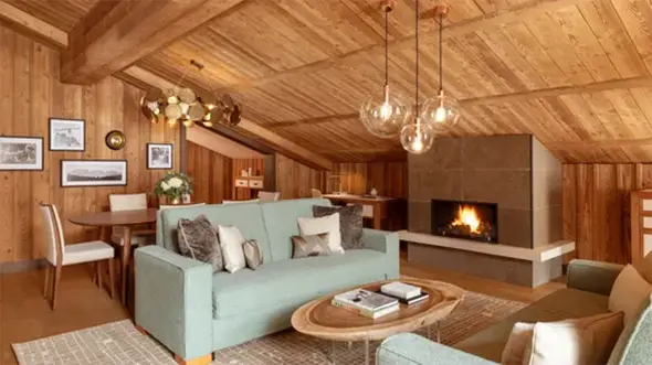 Cozy living room with a fireplace in the Alpine chalet of Fouquet s Courchevel hotel.