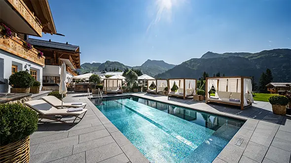 Outdoor pool with sun loungers in a Lech spa hotel.