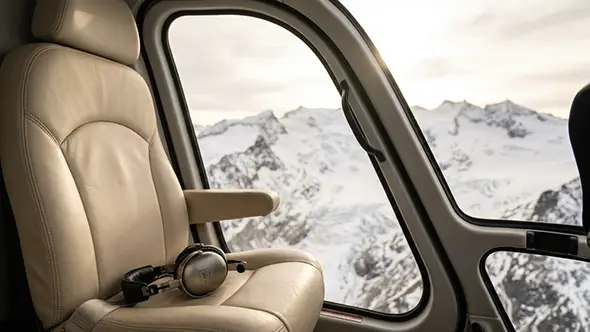 Helicopter interior with leather seats and mountain view.