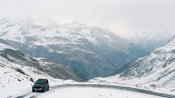 Premium SUV driving on a snowy mountain road.