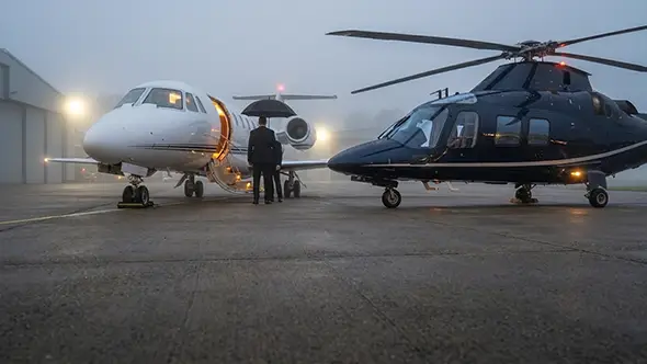 Private jet and helicopter at the airfield in fog.
