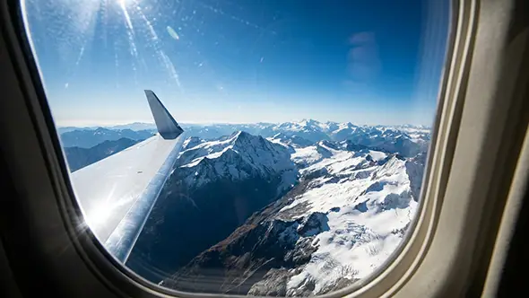 View from a private jet window over snow-covered Alps.