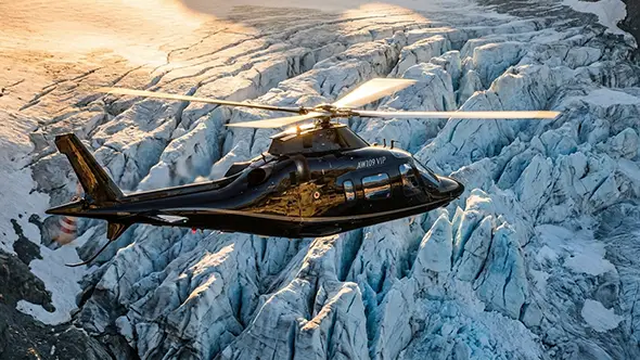 AW109 VIP helicopter flying over an Alpine glacier to St. Moritz.