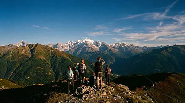 Group of hikers on a ridge overlooking the Mont Blanc massif.