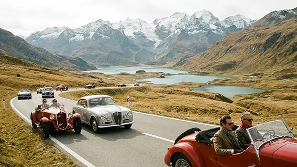 Classic Italian cars driving on a mountain road in Engadin valley.