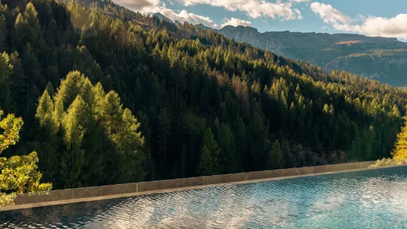 Outdoor infinity pool at Aman Rosa Alpina above a forested Dolomite valley