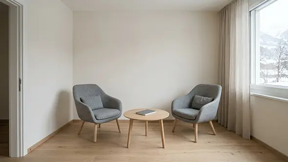 Quiet consultation room with two grey armchairs, a low table and a window onto snow