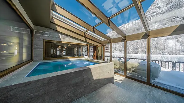 Covered jacuzzi under a heated glass roof with mountain views