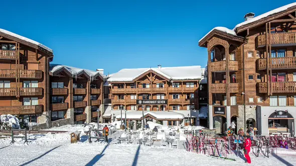 Wooden chalet facade of Fahrenheit Seven Courchevel on the Moriond snow front with skis racked outside