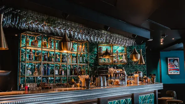 Emerald tiled back bar with brass shelving and hanging glassware at The Seven Kings in Courchevel 1650