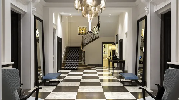 Entrance hall with a black-and-white chequerboard marble floor and a wrought-iron staircase at Hôtel Mont-Blanc Chamonix