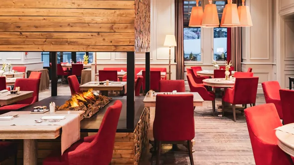 Le Matafan restaurant with red armchairs around a central open fire at Hôtel Mont-Blanc Chamonix