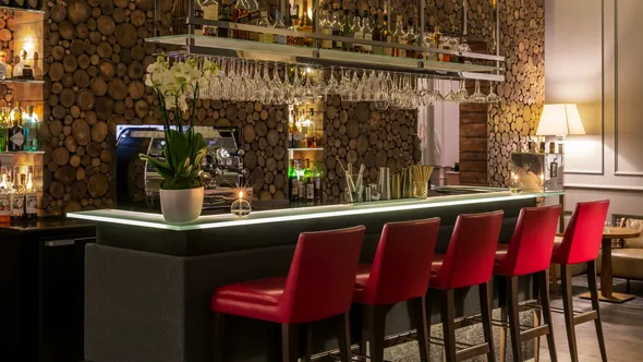 Lounge bar with red bar stools and a log-stack wall at Hôtel Mont-Blanc Chamonix