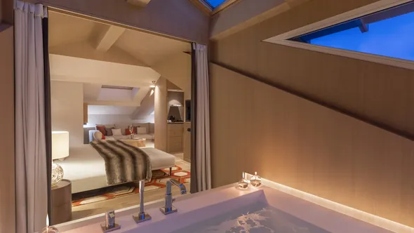 Bathtub in the Penthouse Suite under the roof, with the bedroom beyond, at Hôtel Mont-Blanc Chamonix