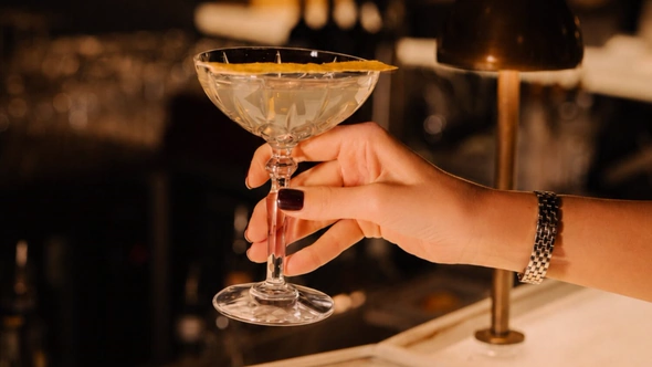 Cut-crystal coupe held at the bar under warm amber light at Le Saint Roch Courchevel
