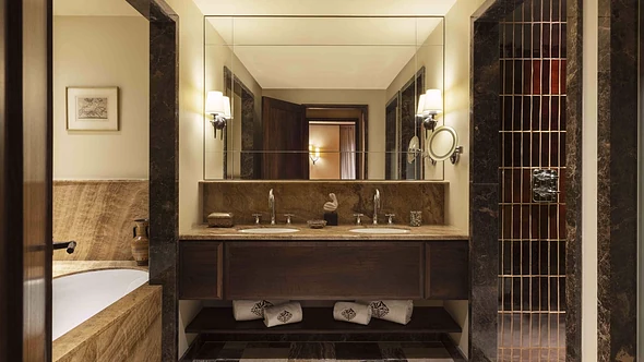 Marble bathroom with twin basins, brass tiled shower and embroidered towels at Le Saint Roch Courchevel
