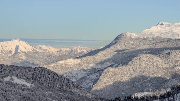 Snow-covered ridges and forested valleys of the Three Valleys in low winter light