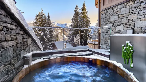 Outdoor wooden hot tub on a snowy spa terrace at Lys Martagon, Courchevel 1850