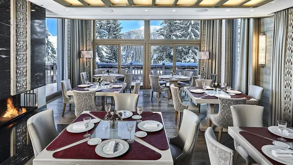 Panoramic restaurant with snowy fir trees beyond the windows at Lys Martagon, Courchevel 1850